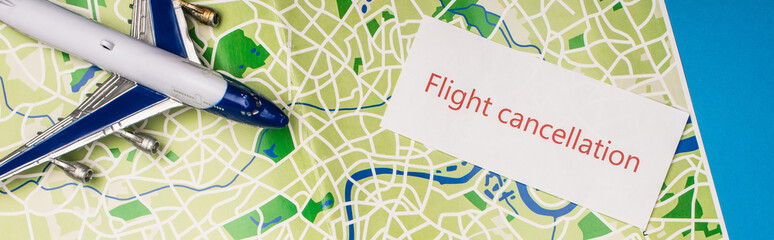 Top view of card with flight cancellation near toy plane on map isolated on blue, panoramic shot