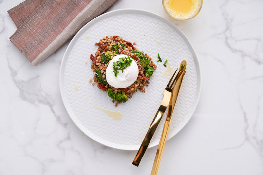 Healthy and gluten free breakfast of buckwheat with broccoli and sun-dried tomatoes topped with a poached egg