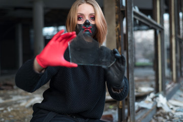 Fototapeta premium beauty portrait of a beautiful girl in a black mask with rhinestones, cool designer makeup. The girl is crying emotionally, holding a broken glass in her hand.