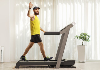 Bearded man in sportswear exercising on a treadmill at home