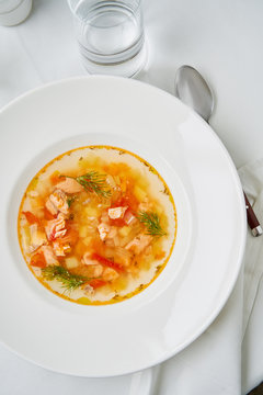 Clear fish soup served with vegetables in a white plate