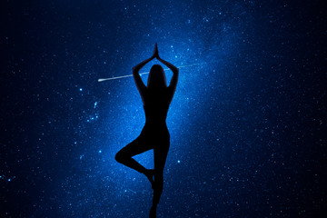 Woman with yoga pose in front of the universe