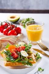 Served breakfast with savory waffles, boiled egg, tomato and microgreen on light background. Appetizers, snack, brunch. Delicious healthy food concept.