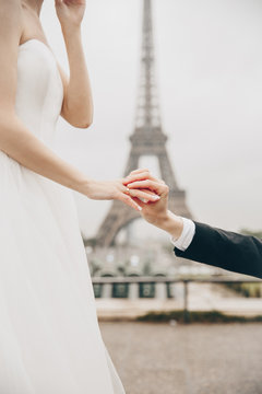 Bride and groom having a romantic marriage in Paris. Wedding couple on a background of Eiffel Tower in Paris. Romantic date, wedding ceremony in France. Bride in wedding dress. Wedding ring
