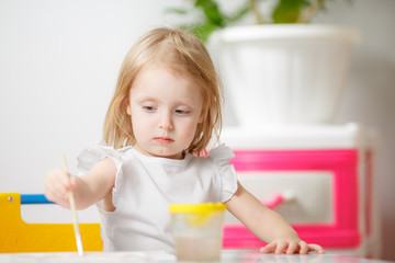 pretty kid girl painting with watercolours at home