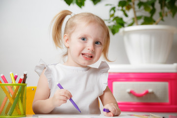 Little Baby Girl Painting At Table In Home Or Kindergarten Preschool. Cute Adorable Small Child With Two Pony Tails Drawing Indoor.Box With Multicolored Marker Pens.