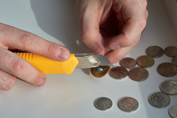 A man counts money and divides it. Round coins. Cutting of money with a knife