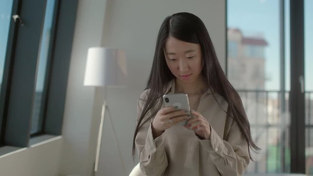 Beautiful young asian girl manager of a large company chatting with her boyfriend using a smartphone and high-speed Internet. Concept of communication during a break at work