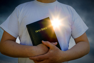 Man holding a Bible with glowing heart sun