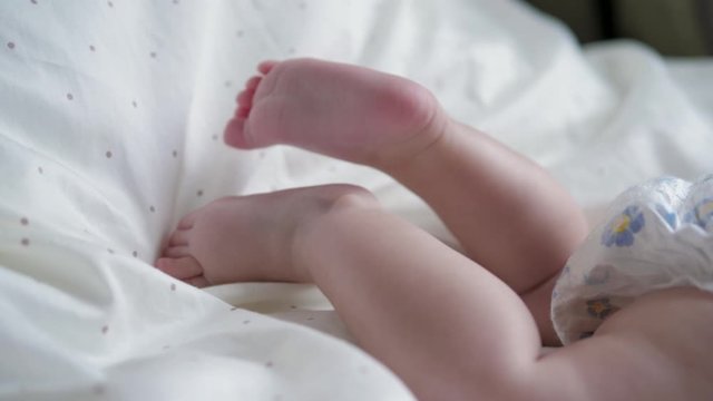 Close Up Of A Newborn Baby Dangling Small Feet With Fingers In The Crib