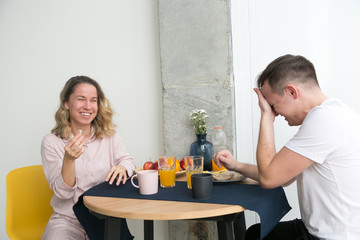 Cute couple having breakfast together at home in the kitchen