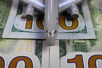 Airplane model on runway of 100 dollar paper money bills (focus on 100)
