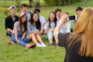Happy young group of friends taking picture with phone together at the park