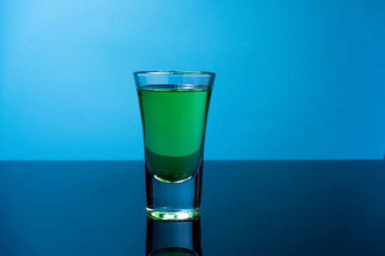 A glass of green drink. Glass of tequila on a blue background.