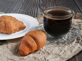 Fragrant croissants on a white plate and hot coffee. The concept of a quick breakfast at the workplace or breakfast with you.
