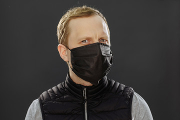 In a black mask. Quarantined man. On a black background. Quarantine covid-19. Stay at home.