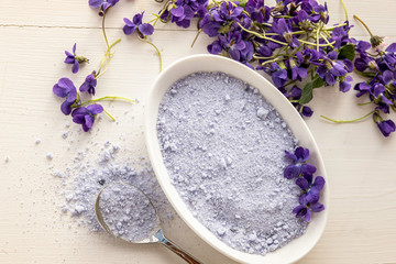 Fototapeta na wymiar viola violeta odorata violet natural sugar bath salt on white background in porcelain dish 