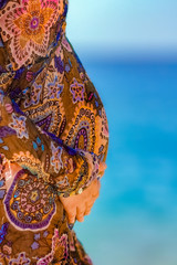 A Pregnant girl near the sea background. A happy woman with a hat on vacation while traveling.