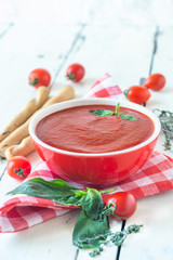 tomato soup with basil, breadsticks on white background 