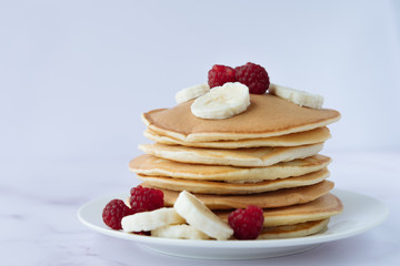 breakfast, pancakes with raspberry and banana on a white plate
