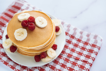 breakfast, pancakes with raspberry and banana on a white plate