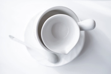 minimal style tableware. minimalism in trendy house interior. white tea cup, plate and saucer on a table. scandinavian style and design. simple and clean kitchenware. 