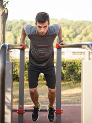 Male athlete exercising on parallel bars outdoor