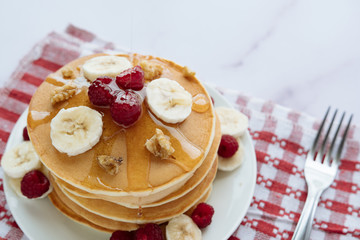 breakfast, pancakes with raspberry, nuts, banana and honey on a white plate