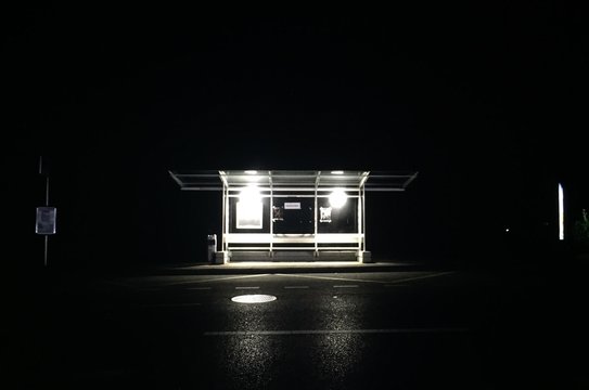 Illuminated Bus Stop On Roadside At Night