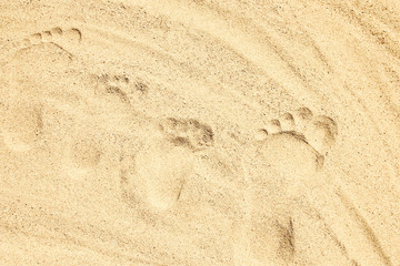 Fototapeta na wymiar A Drawing in the sand near the sea in nature travel background. Hand drawn footprint on vacation.
