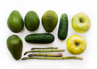 Top view, green vegetables on white. Composition of vegetables: apples, avocado, asparagus, cucumber. Vegetarian Feeding.