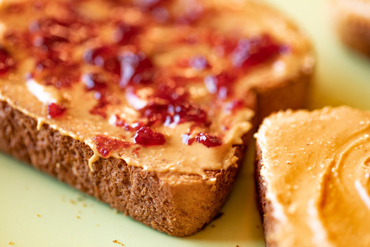 Creamy peanut butter spread with jelly on healthy whole wheat toast bread, close-up