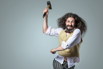 Portrait of an eccentric, aggresive man holding a hammer