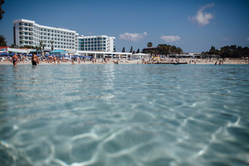 Clear water in the sea with hotel in the background