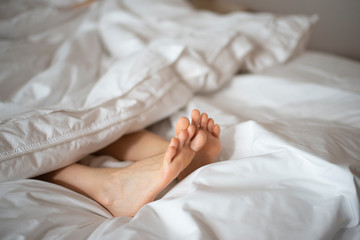 Female feet peeking out from white blanket