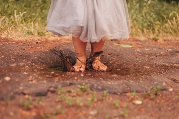 Outdoor summer picture of little girl in a grey skirt jumping in a puddle
