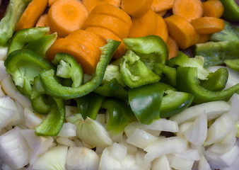 Three horizontal rows of chopped vegetables - orange carrots, green paprikas and white onions. Concept of food ingredients, vegetarian cuisine, healthy food, organic vegetables.
