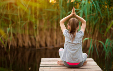 Girl meditating at sunrise on the beach near river