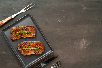 Grilled Beef steaks served with rosemary on  metal tray, close up