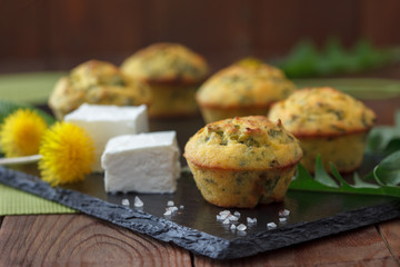 Fresh homemade muffins with cheese and nettle on wooden table. Healthy snack muffins with feta cheese and nettle.