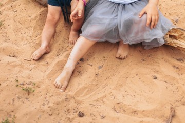 Outdoor summer picture of little boy and girl brother and sister playing in sand with bare feet on a warm day