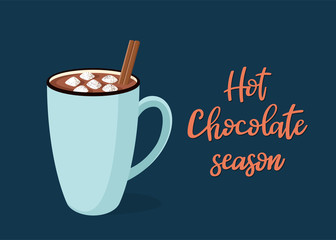 Hot chocolate with marshmallow in a blue mug on a dark blue background. Handwritten text 