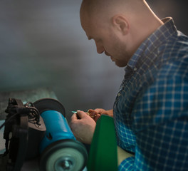 Naklejka premium Master sharpens scissors on special equipment for sharpening tool