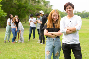 Fototapeta na wymiar Happy young Asian couple together with friends at the park