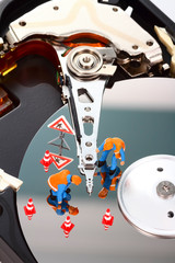 Conceptual image of miniature figure people looking for problems on a computer hard drive