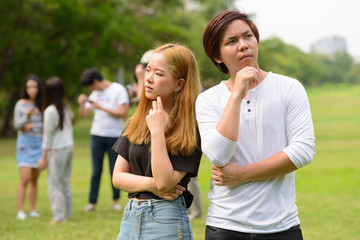 Young Asian couple thinking together with friends at the park