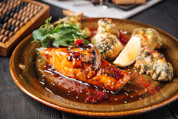 Closeup on fried salmon in batter with vegetables and sauce, horizontal format