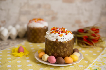 Fresh beautiful Easter cake on the plate with glaze and decorative egg candies and flowers on a bright yellow background