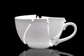 white ceramic cup broken into fragments as a result of the fall and glued together chewing gum in...
