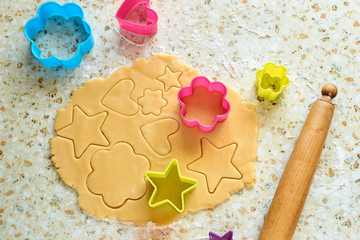 A child with his mother makes cookies, rolls out the dough and uses forms to make cookies.